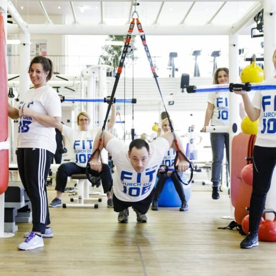 Mitarbeiter trainieren im Fitnessstudio: Firmenfitness 'Fit durch den Job' mit TRX, Hanteln, Kettlebells und Boxsack