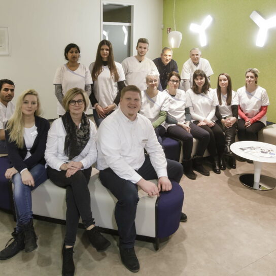 Gruppenfoto des Praxisteams im Wartebereich – freundliches medizinisches Team in moderner Arztpraxis.