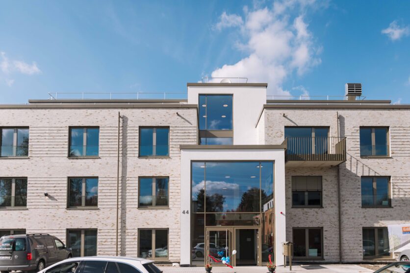 Modernes Wohn- und Bürogebäude Nr. 44 mit Klinkerfassade, großen Glasfronten und Balkon, Frontansicht bei blauem Himmel